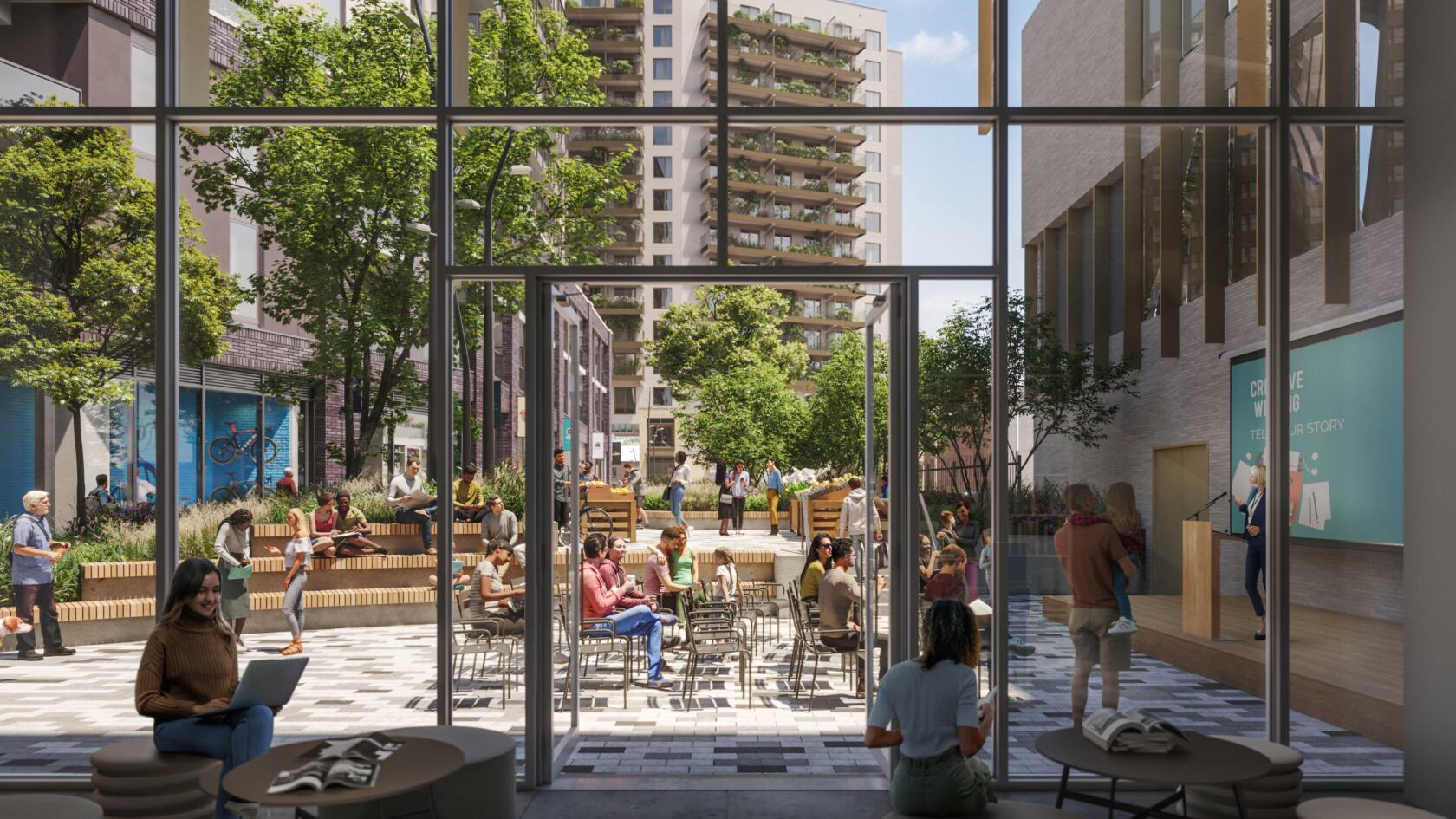 Looking through large windows to busy courtyard with people sitting on benches and chairs watching presentation of someone standing at podium with screen behind.